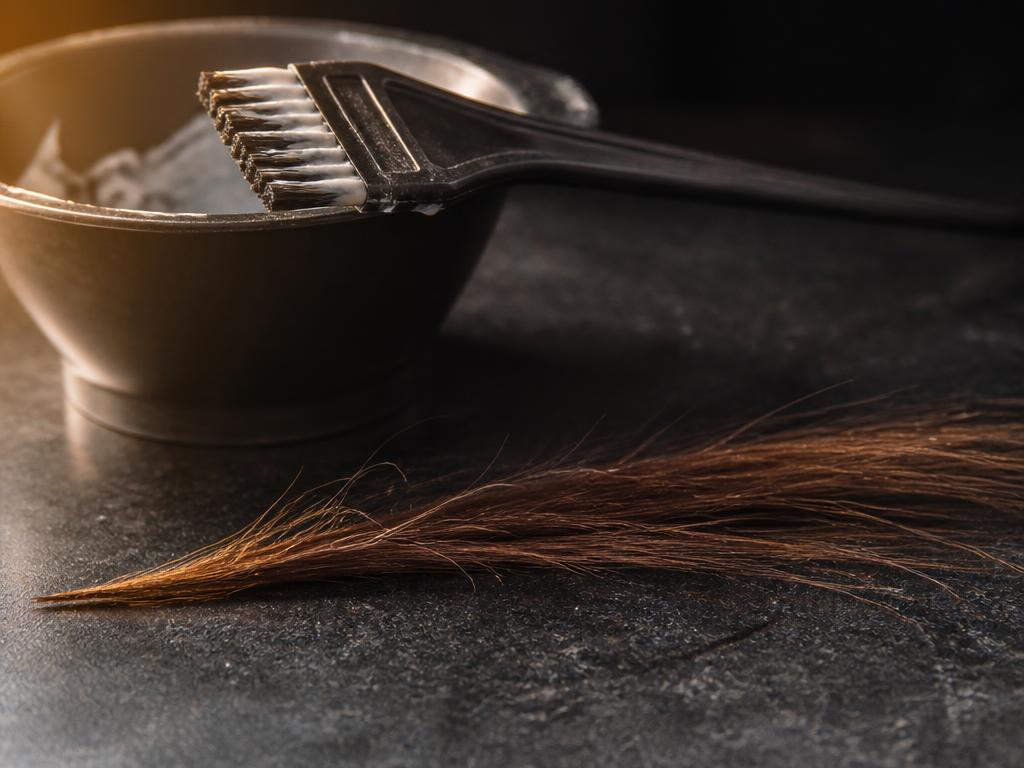Mecha de cabelo avaliada ao lado de tigela e pincel de coloração